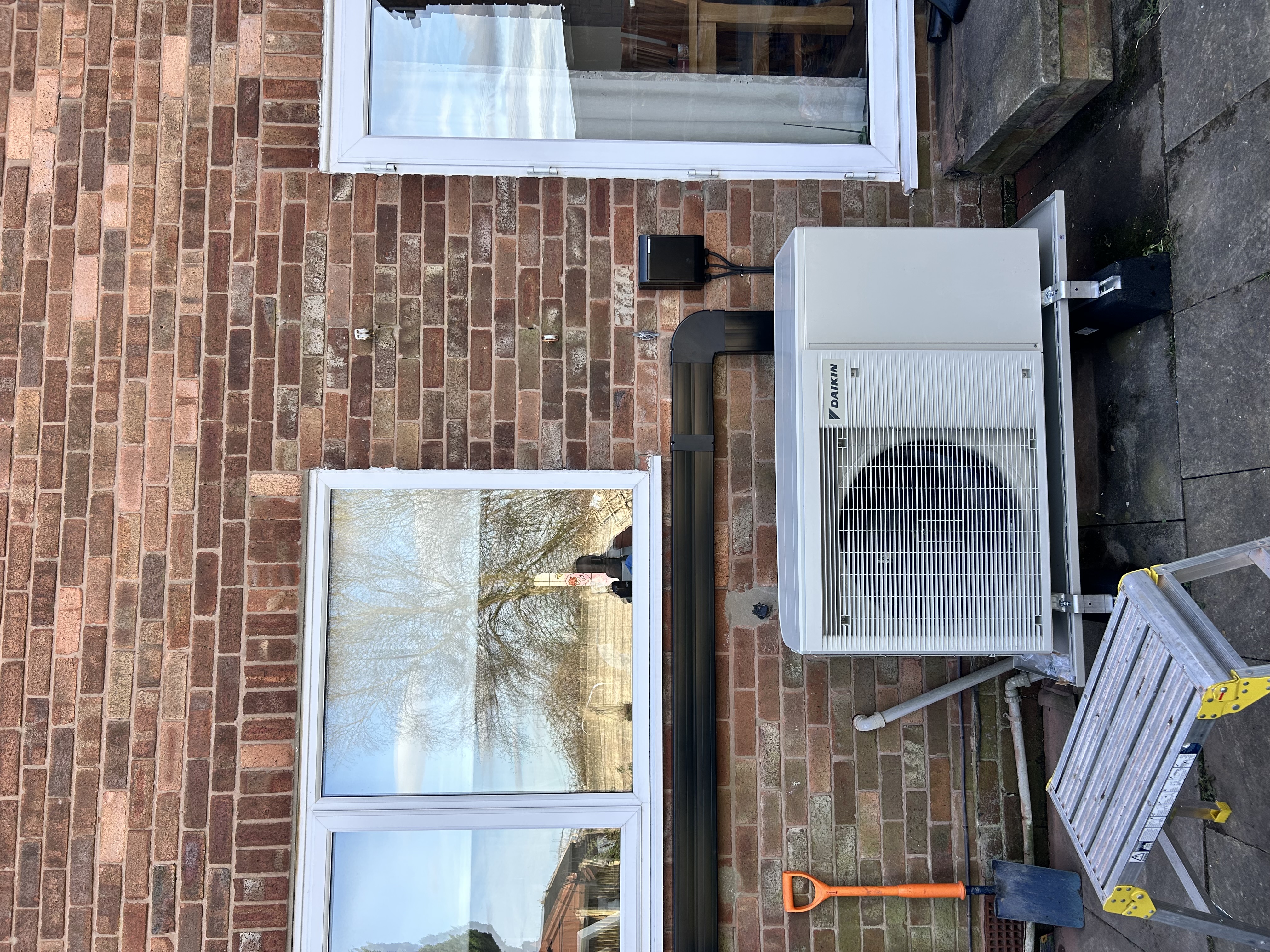 Daikin air source heat pump installed with neat external trunking on a brick house